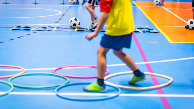 Bērns sporta zālē izpilda vingrojumu