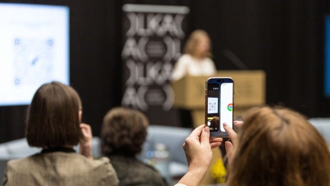 Valsts pētījumu programmas CERS noslēguma konference. Konferences apmeklētāja ar telefonu fotografē notiekošo.