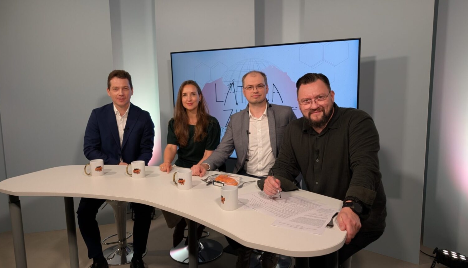 Latvijas Universitātes vadošais pētnieks Artis Kinēns, “BioPhoT” mentore Kaija Kurme-Jansone, projekta biznesa attīstītājs Jurijs Jastržembskis un raidījuma vadītājs Gustavs Terzens Radio SWH TV studijā