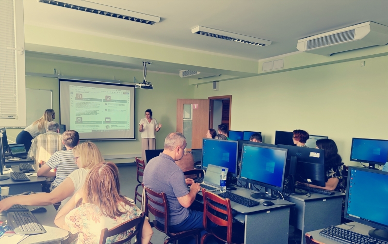 Semināra dalībnieki sēž pie datoriem mācību telpā