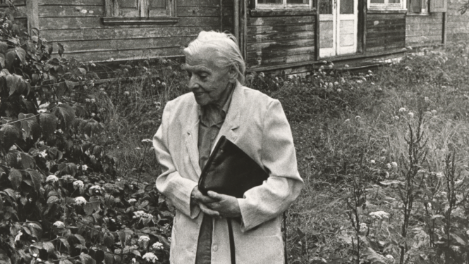 Melnbalts foto ar veca gadagājuma sievieti pie vecas lauku mājas