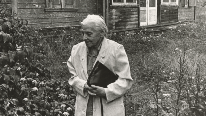 Melnbalts foto ar veca gadagājuma sievieti pie vecas lauku mājas