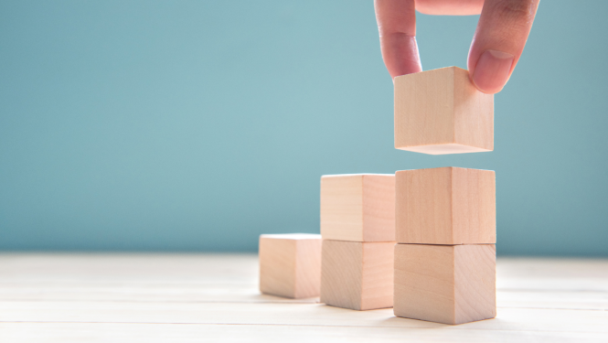 Ilustratīvs attēls ar koka klucīšiem un roku